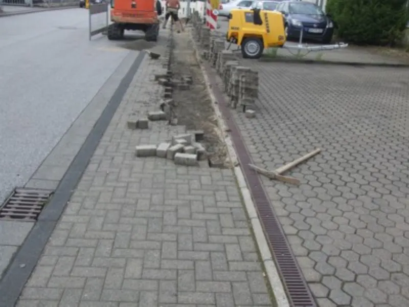 Neu gepflasterter Gehweg mit Entwässerungsrinne an einer Straße